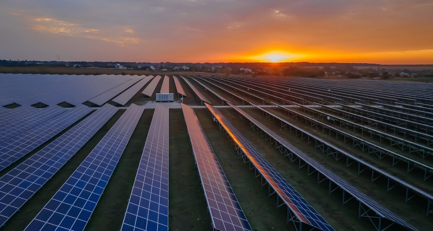 Aerial drone view into large solar panels at a solar farm at bright sunset. Solar cell power plants.