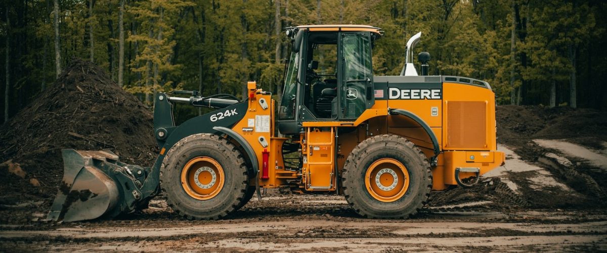 a tractor is parked in the dirt near a pile of dirt